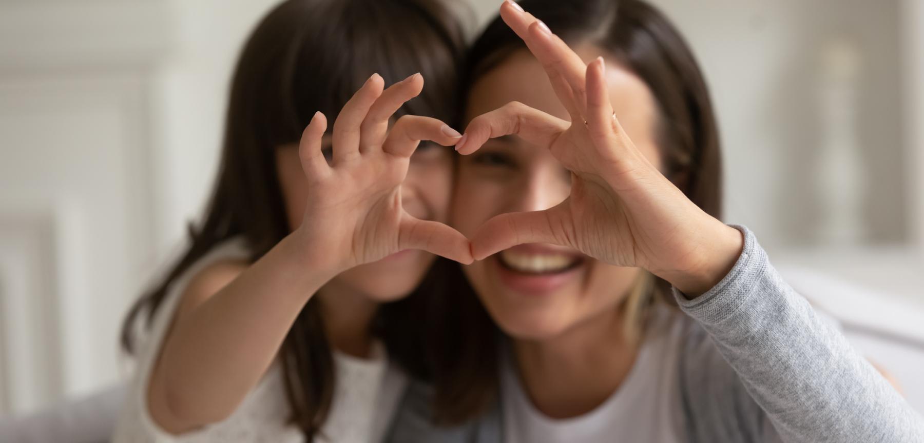 Mother and daughter making heart out of hands